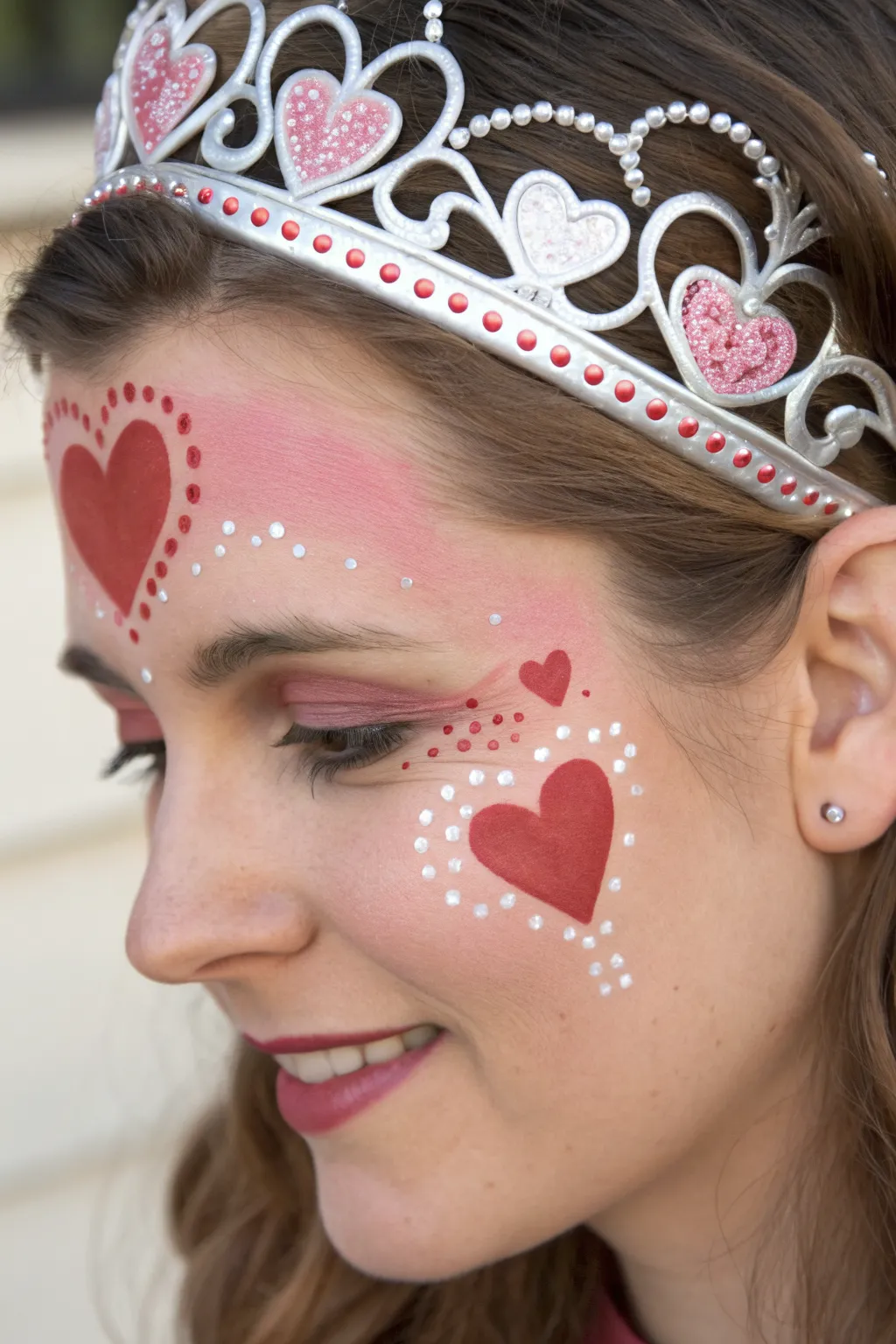 Valentine heart tiara face paint with pink-red layers, dotted jewels, and soft boho calm