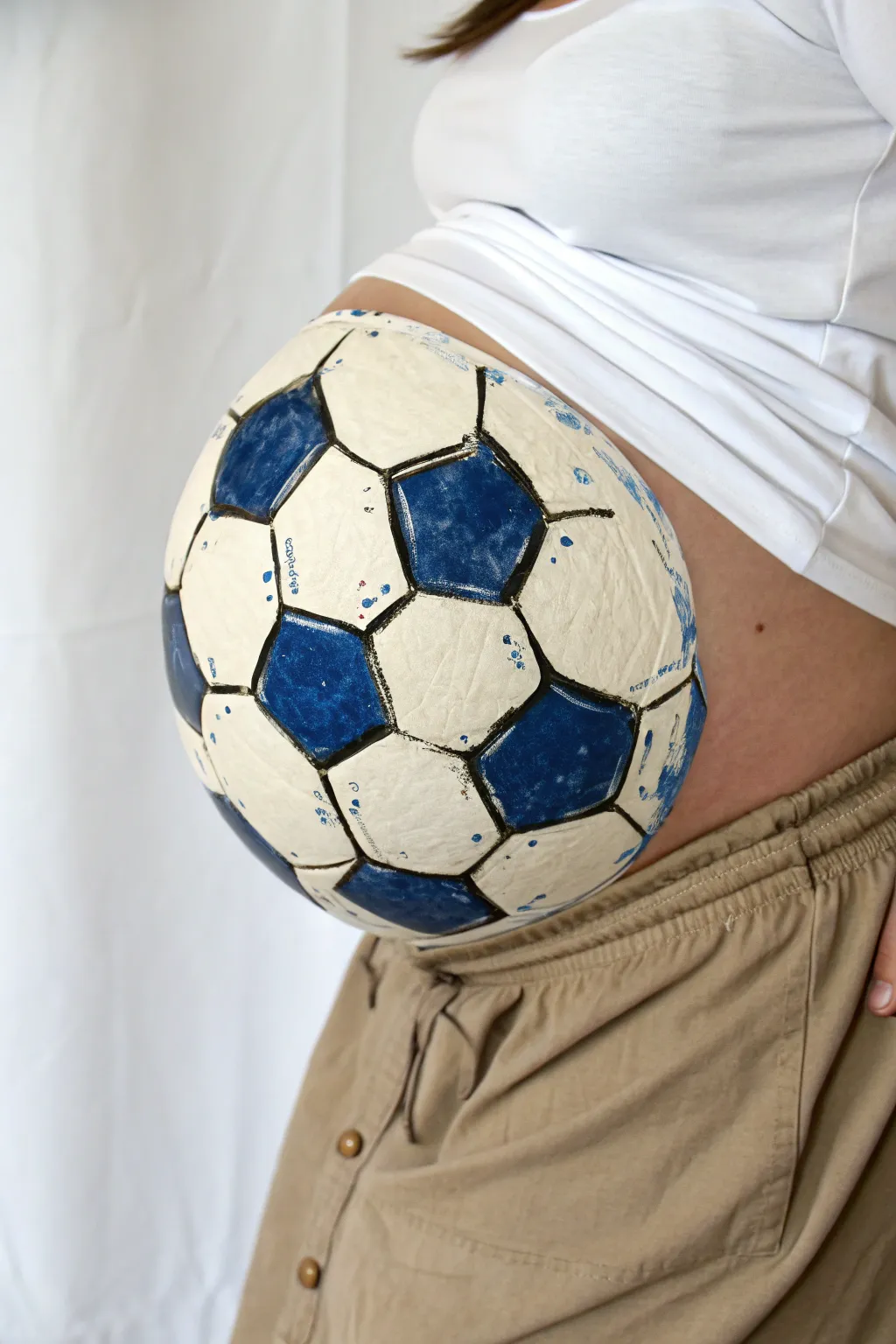 Minimalist soccer ball belly paint with soft blue accents, clean Scandinavian boho vibe