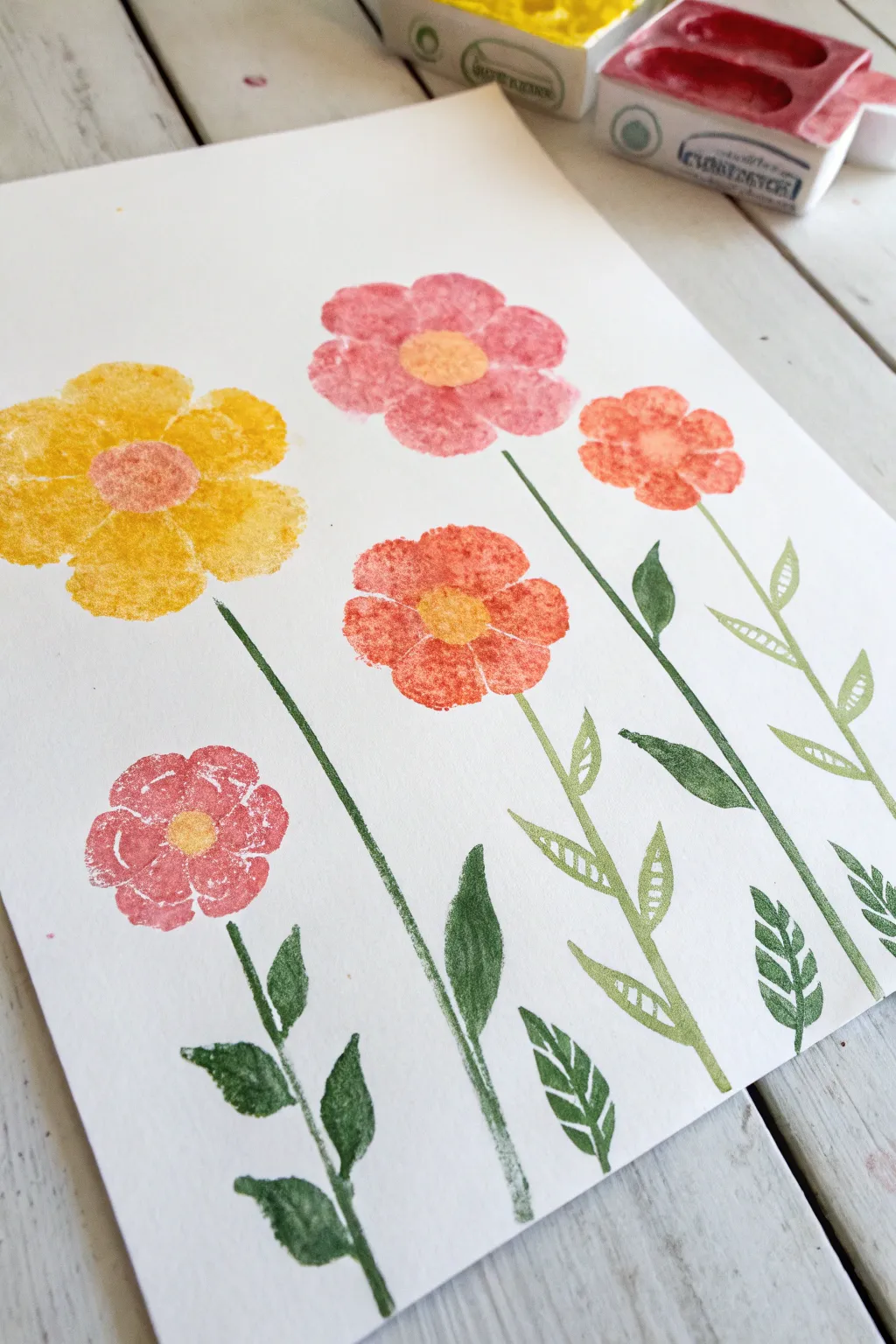 Cheerful sponge-stamped acrylic flowers with simple one-stroke stems on a clean light backdrop