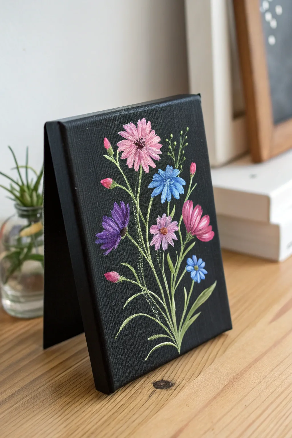 One-stroke wildflowers in bright pinks, blues, and purples popping beautifully on black canvas.