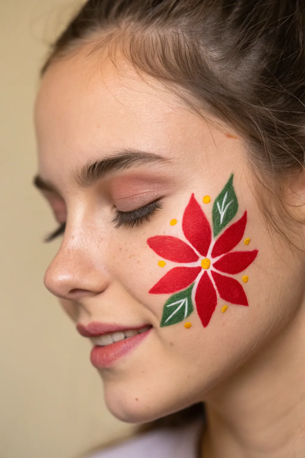 Easy poinsettia corner face paint: bold red petals, yellow center, and two green leaves.
