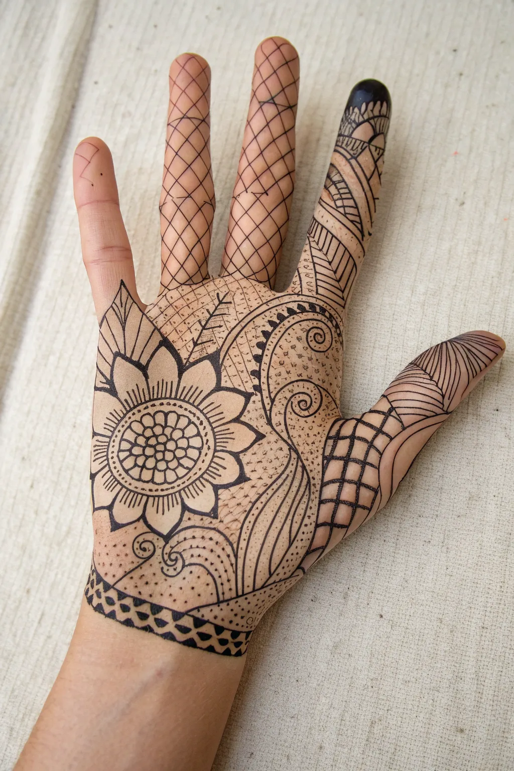 Zentangle patchwork doodles flowing over the back of the hand, crisp ink on soft skin.