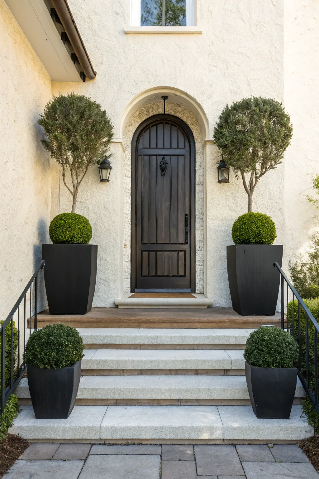 Symmetrical stoop inspiration: clean steps, dark wood door, matching planters and soft greenery.