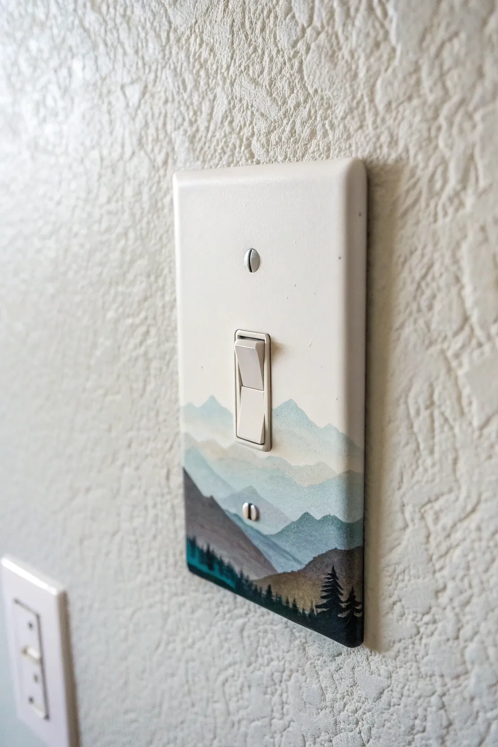 Tiny mountain landscape painted on a light switch cover, clean horizons and modern contrast