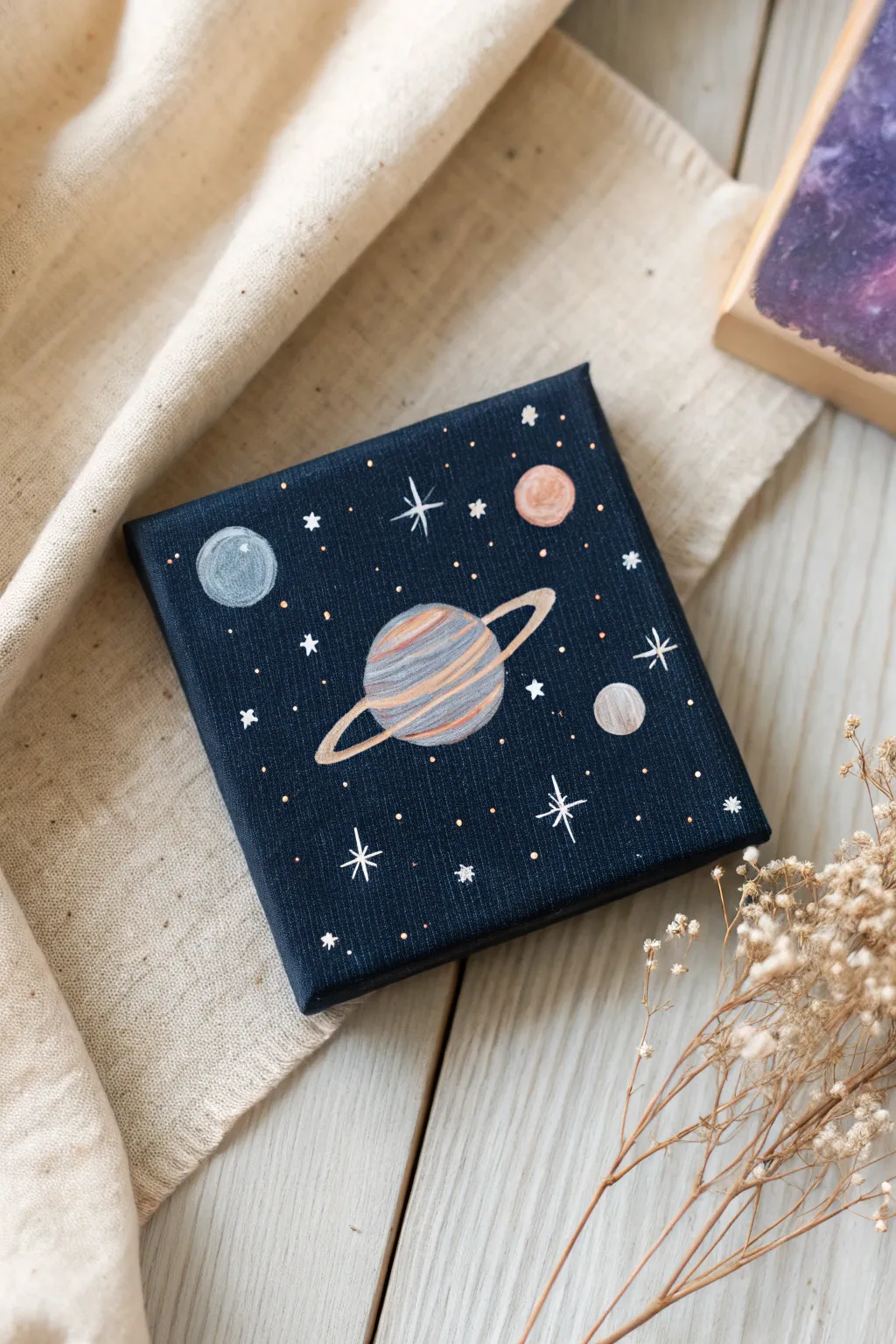 Mini canvas planets on a starry night backdrop, minimalist Scandinavian-boho space painting idea.
