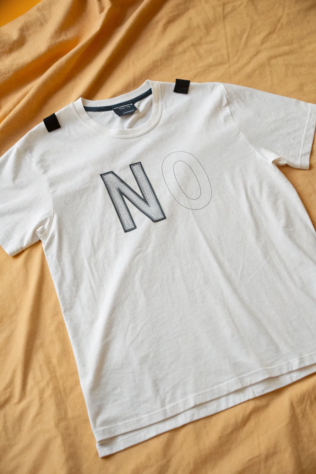 Crisp stencil letter layers on a neutral tee, showing clean edges and handcrafted ink texture.