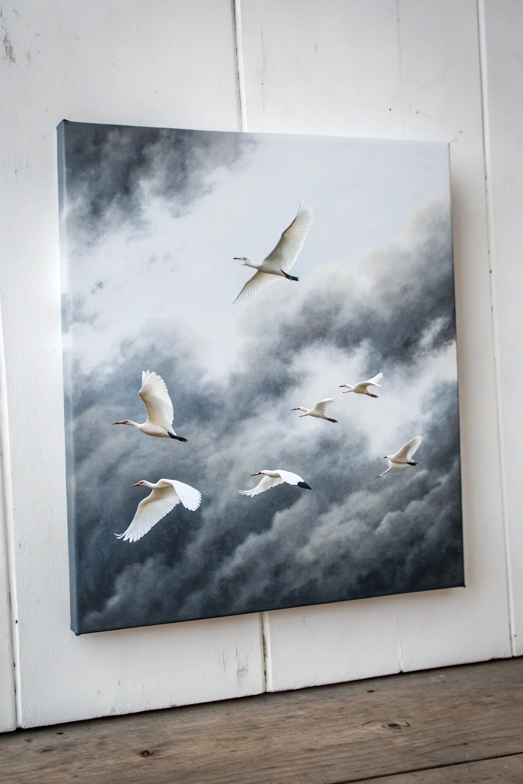White birds in motion on a moody storm-sky canvas, minimalist contrast with soft brushy clouds.